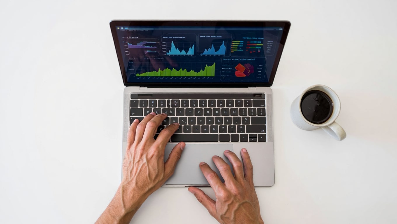 hands-typing-on-laptop-with-financial-charts-and-coffee