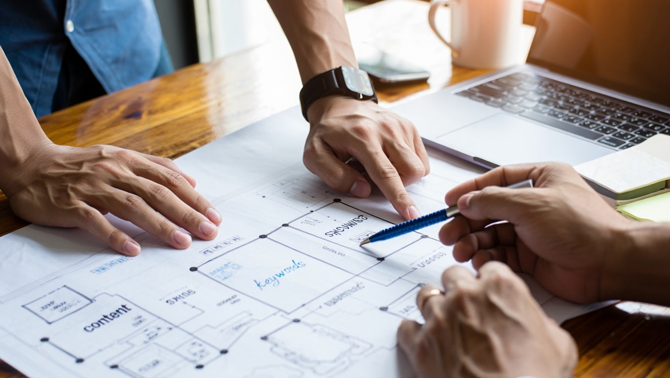 team-collaborating-on-project-plan-with-blueprints-and-laptop